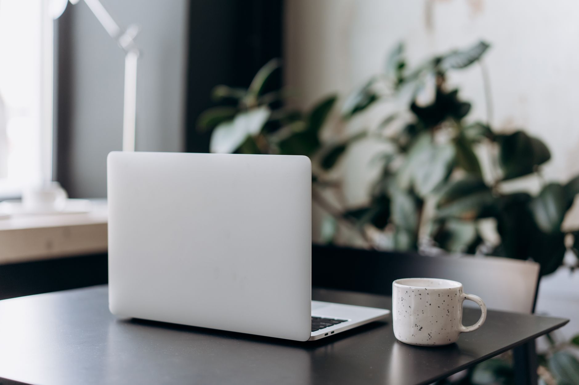 Poste de travail minimaliste avec un ordinateur portable fermé et une tasse de café sur une table.